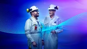 Two ship engineers in white protective gear looking at each other while smiling.