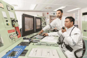 Two MISC maritime engineers monitoring control systems in a ship’s control room.